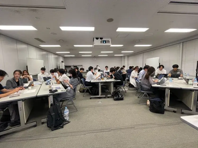 The whole room, with teams drawing at each island of desks