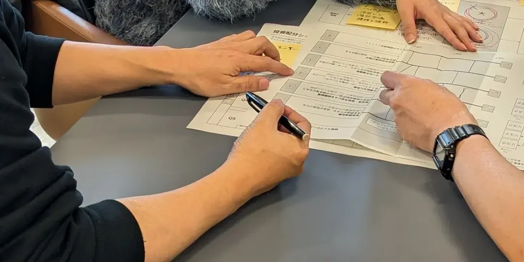 チームが1枚のワークシートを囲み、手を伸ばして書き込んでいる