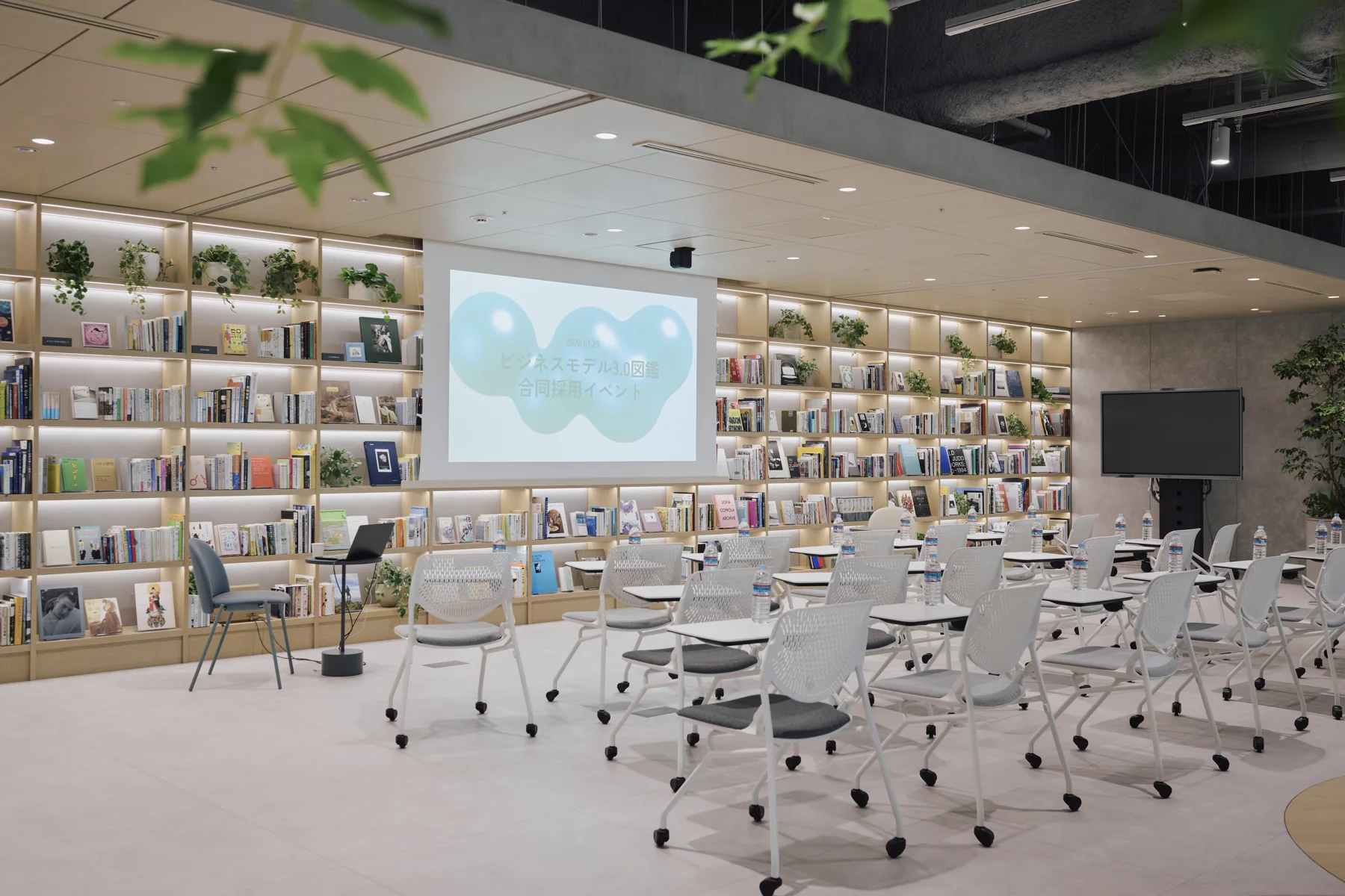 The venue before doors opened: chairs lined up in a room surrounded by bookshelves, with the event title on the screen